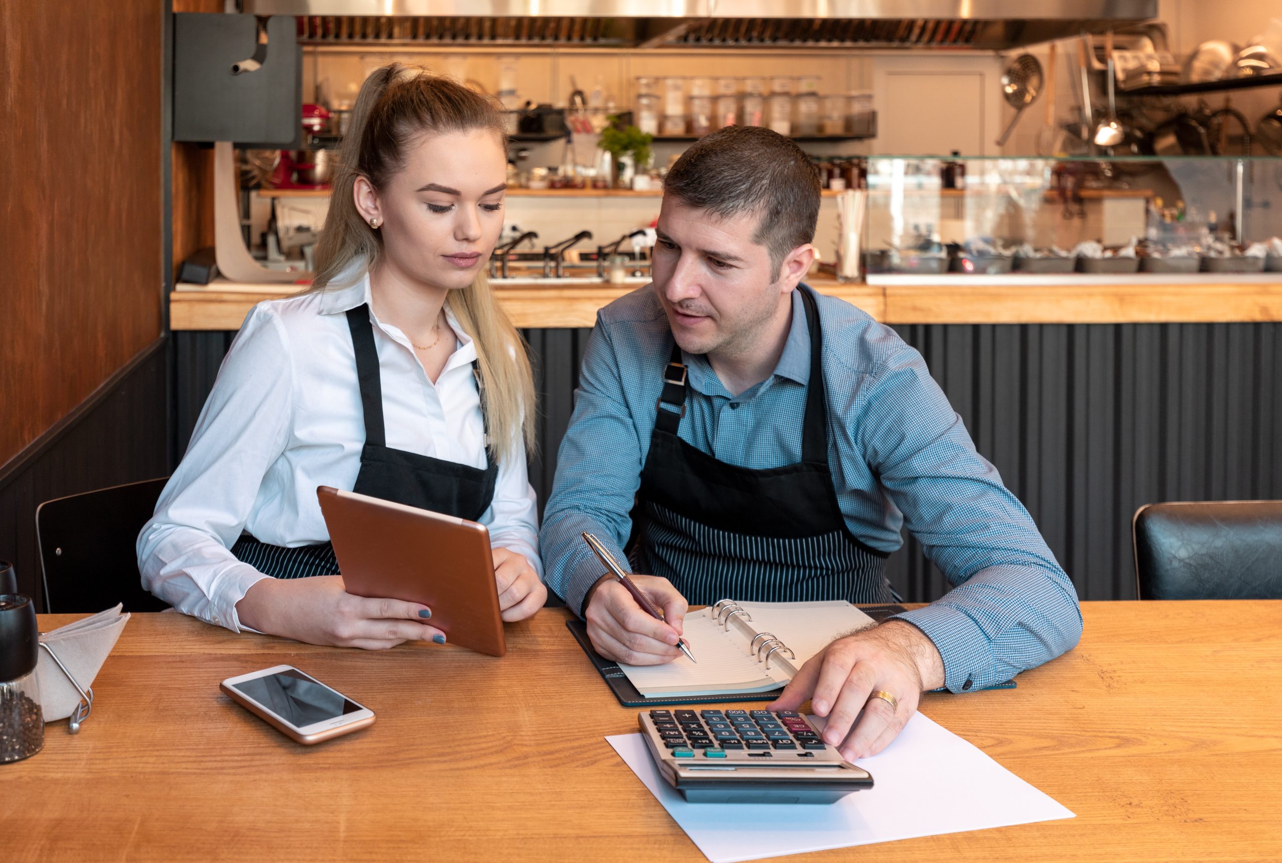 small shop with 2 employees looking at caculator and notebook